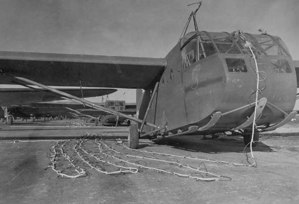 Francja, 23 marca 1945 roku, lotnisko A-58 Coulommiers. Szybowce CG-4A przygotowane do startu do operacji Varsity. Wszystkie szybowce na tzw. podwoziach szkolnych, jakich w tym typie szybowca nie wolno było stosować do operacji bojowych na całkowicie nieznanym rodzaju gruntu, gdyż groziło to kapotażem. Szybowiec na pierwszym planie jest zmodernizowany i ma pod otwieraną sekcją kabinową jeden z wariantów płóz Coreya (szybowiec stojący za nim ma inny wariant płozy Coreya złożony tylko z jednej grubej i szerokiej płozy). Zamiast zamówić prawidłowe dla CG-4A tzw. podwozie taktyczne (odrzucany po starcie wózek kołowy) i lądować prawidłowo na płozach, jak nakazywał konstruktor szybowca, USAAF wolały dodać płozy choć trochę zabezpieczające sekcję nosową przed ryciem ziemi podczas lądowania i blokadą otwierania nosa. Do szybowca podłączona jest patentowa lina nylonowa firmy Du Pont o średnicy 11/16 cala (17,5 mm) – ówcześnie najdoskonalsza lina holownicza świata. Długość liny – 350 stóp (107 m). Linę oplata kabel telefoniczny WT-1/U do dwukierunkowej łączności między szybowcem a jego samolotem-holownikiem. Służyła do tego łącznica AN/AIA-1A. Fot. US Army Signal Corps